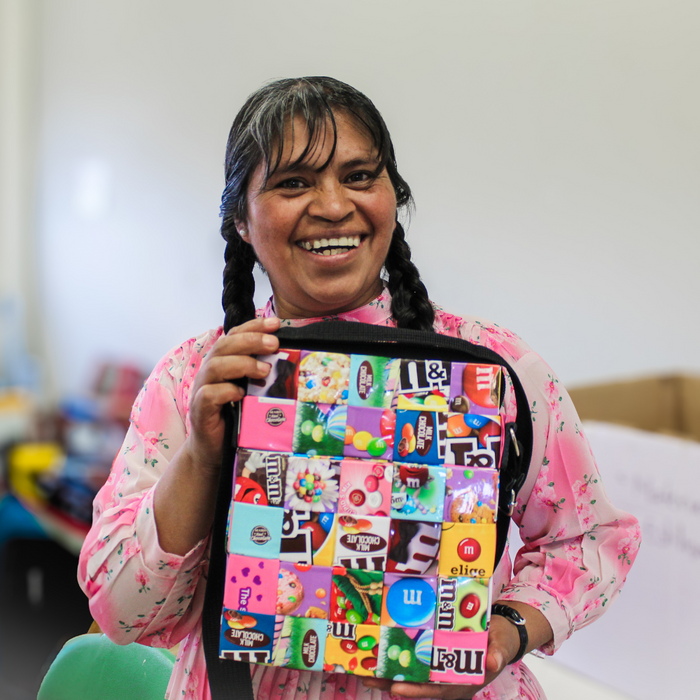 Mujer sonriendo mientras sostiene un bolso MITZ tejido con envolturas de dulces